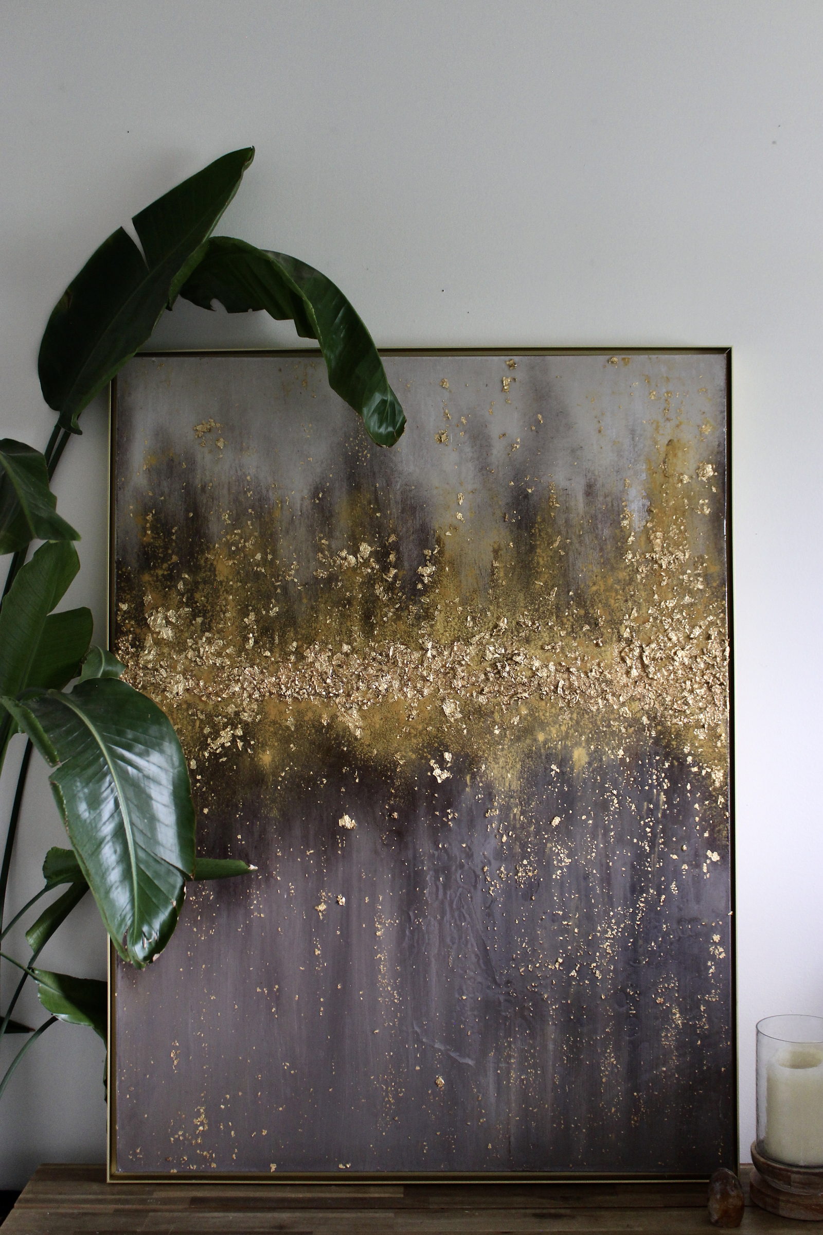 Gilded Earth by Jessica Malie, gold leaf and resin on canvas, framed and leaning against a wall