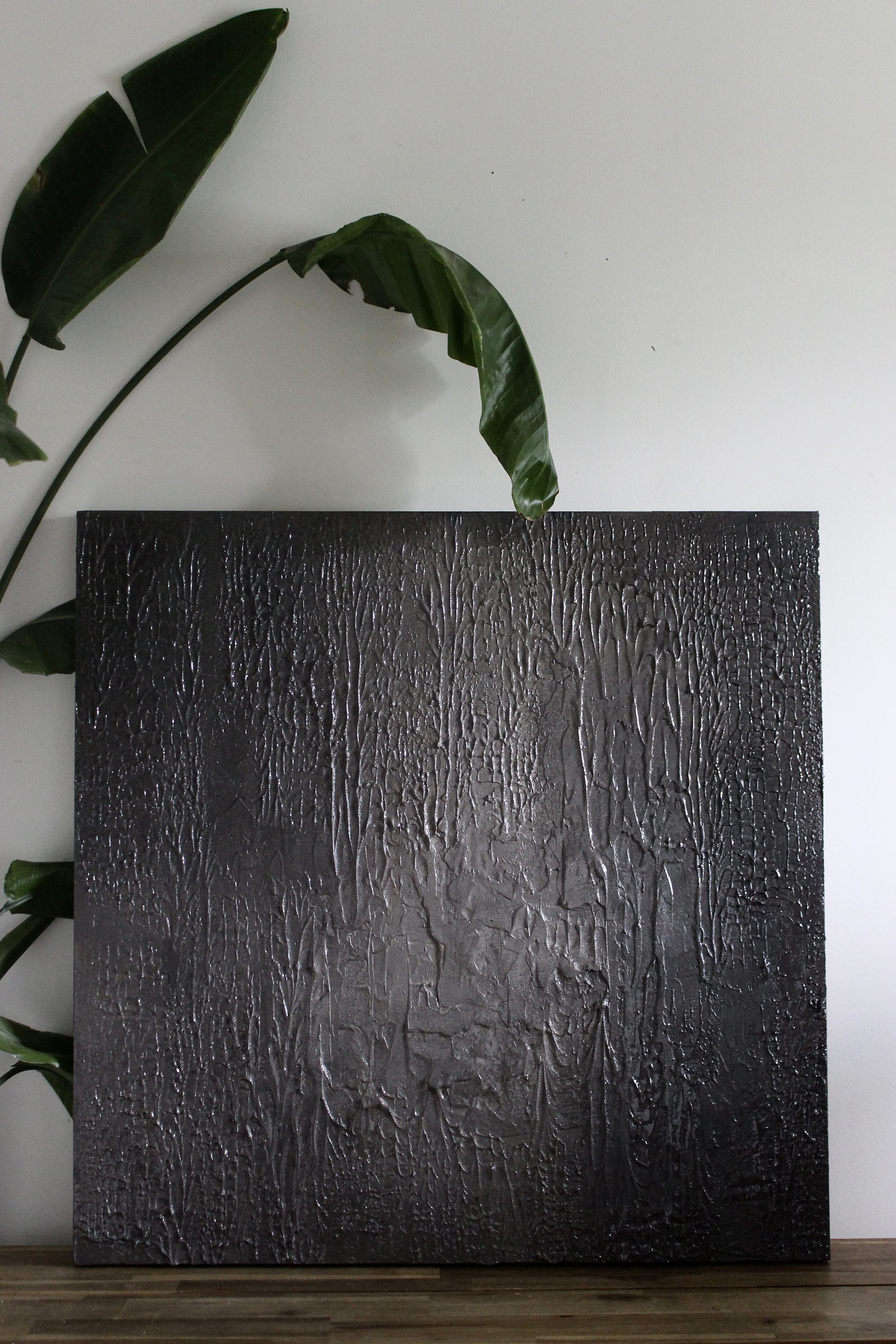 Obsidian, a black sculptural texture canvas resting on a wooden bench